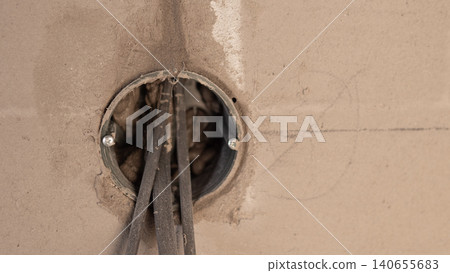 Cables Emerging From Circular Junction Box, Insulation Stripped And Conductors Visible, Rough Plaster Edge, Close Viewpoint Revealing Core Electrical Components And Prep Work 140655683