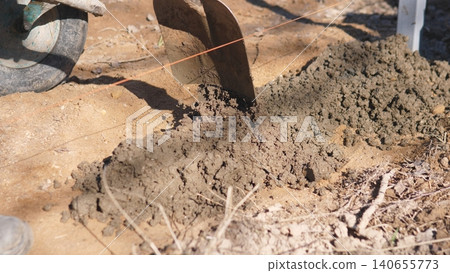 Mortar Applied On Foundation. Workers Spreading Fresh Mortar Along Foundation. Hands Carefully Guiding Blocks Into Position As Fresh Mortar Is Spread Along Foundation Course Mortar Applied On Foundation. Workers Spreading Fresh Mortar Along Foundation. Hands Carefully Guiding Blocks Into Position As Fresh Mortar Is Spread Along Foundation Course 140655773