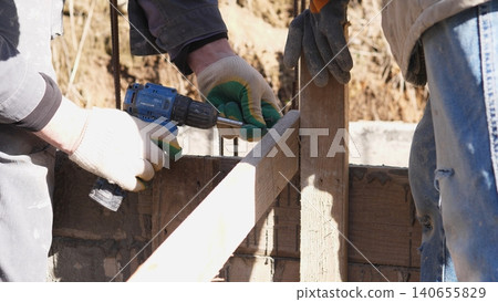 Measuring And Marking Building Materials. Closeup Of Skilled Worker Measuring Wood. Close Examination Of Carpentry Tools Used For Accurate Framing Measurements In Sunlight Measuring And Marking Building Materials. Closeup Of Skilled Worker Measuring Wood. Close Examination Of Carpentry Tools Used For Accurate Framing Measurements In Sunlight 140655829
