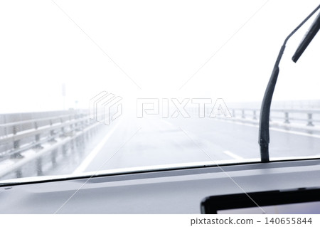 由於濃霧瀰漫,車內能見度很差。雨刷正在運轉。眼前的景色模糊不清。 由於濃霧瀰漫,車內能見度很差。雨刷正在運轉。眼前的景色模糊不清。 140655844