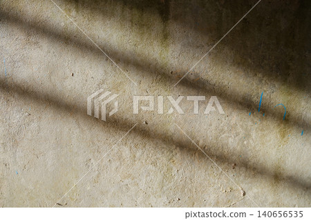 Concrete wall texture with diagonal shadow stripes. Weathered beige concrete wall surface with diagonal shadow lines cast by bars, 140656535