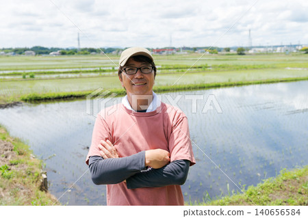 A farmer smiles with his arms crossed. 140656584