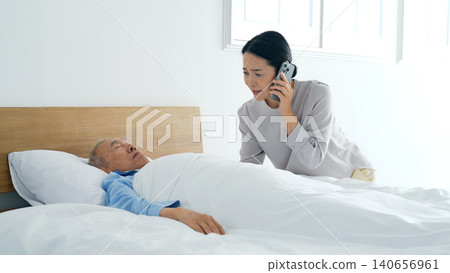一名女子用智慧型手機與一名昏迷不醒的老年男子通話。 一名女子用智慧型手機與一名昏迷不醒的老年男子通話。 140656961