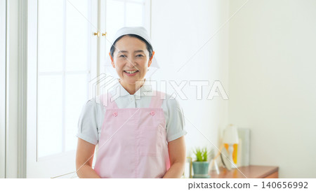 A smiling middle-aged woman wearing an apron. A smiling middle-aged woman wearing an apron. 140656992