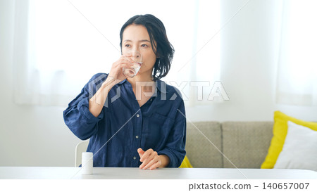 Middle lady drinking water in the room 140657007