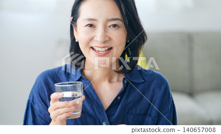 Middle lady drinking water in the room 140657008