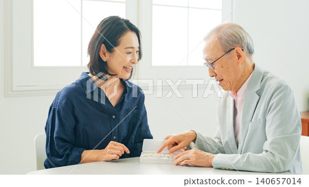 一位女士向一位老年男性講解藥物知識。 140657014