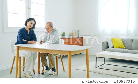 A senior man and a middle-aged woman pondering while taking notes. 140657019