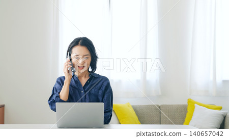 Middle-aged woman using a smartphone in a room Middle-aged woman using a smartphone in a room 140657042