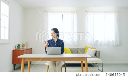 Middle-aged woman using a smartphone in a room Middle-aged woman using a smartphone in a room 140657045