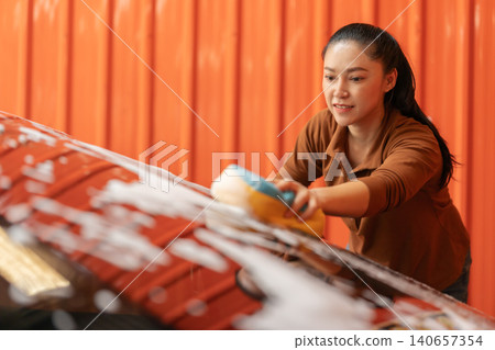 woman washing car with sponge and foam in a self-service car wash station woman washing car with sponge and foam in a self-service car wash station 140657354
