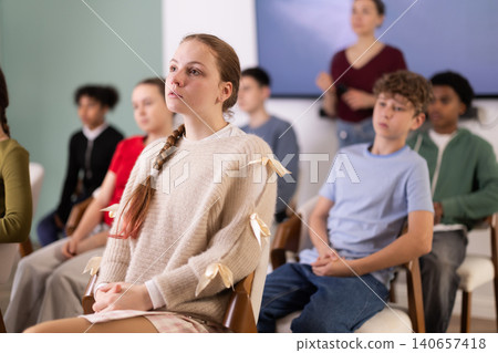 Teenage students listening to lecture while teacher stands in background Teenage students listening to lecture while teacher stands in background 140657418
