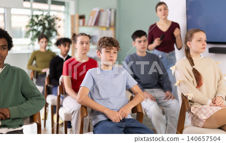 Teenage students listening to lecture while teacher stands in background 140657504