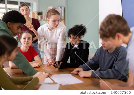 At round table meeting, teen participants discuss problem and try to find solution, teacher watching At round table meeting, teen participants discuss problem and try to find solution, teacher watching 140657560