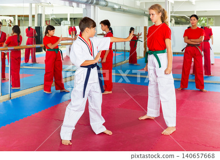Young girls and boys sparring during karate training Young girls and boys sparring during karate training 140657668