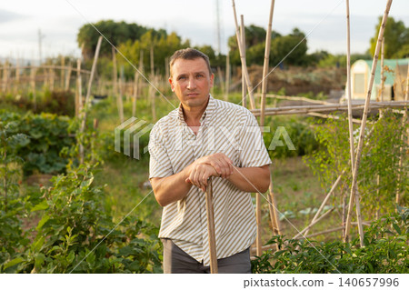 Male farmer farmer with rake standing at farm outdoor 140657996