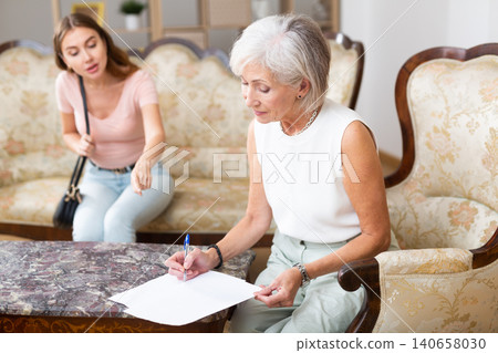 Woman realtor helping elderly woman to sign an apartment lease agreement Woman realtor helping elderly woman to sign an apartment lease agreement 140658030