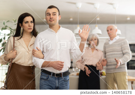 Exiting couple with man making cease argument gesture to parents Exiting couple with man making cease argument gesture to parents 140658178