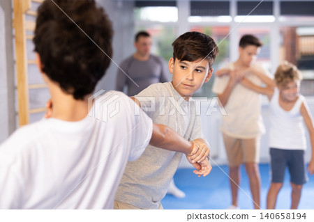 Teen boys practicing basic skills in training bout during self defense course Teen boys practicing basic skills in training bout during self defense course 140658194