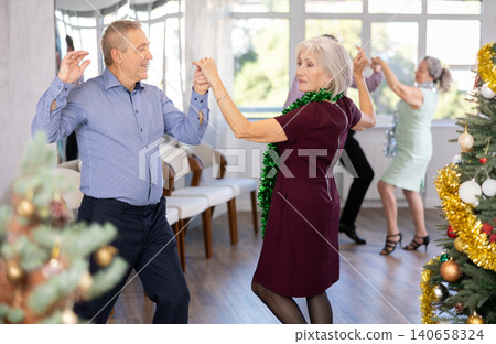 In studio decorated for New Year, elderly man and woman perky dance pair discofox. In studio decorated for New Year, elderly man and woman perky dance pair discofox. 140658324