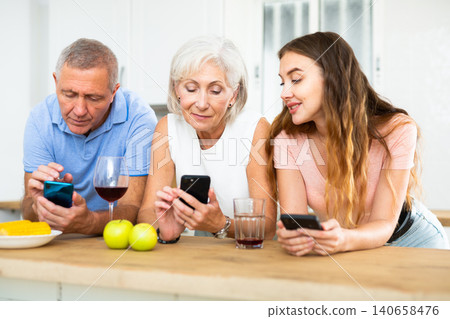 Portrait of family using phones during dinner indoors Portrait of family using phones during dinner indoors 140658476