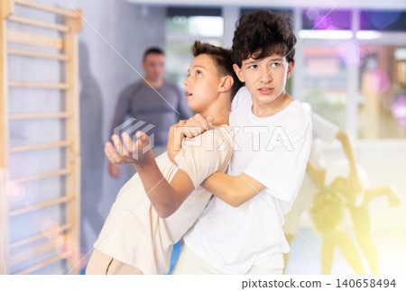 Sporty boys are practices self-defence moves in pairs doing throw over shoulder in sports studio Sporty boys are practices self-defence moves in pairs doing throw over shoulder in sports studio 140658494
