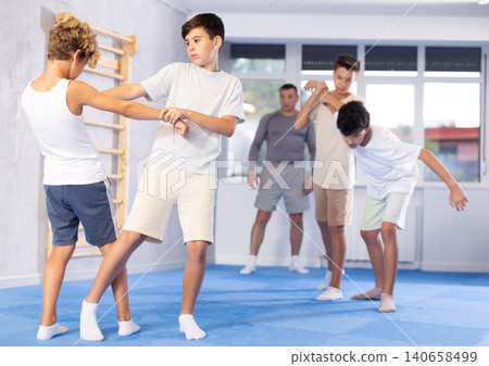 Sporty boys practices self-defence moves in pairs in sporty gym Sporty boys practices self-defence moves in pairs in sporty gym 140658499