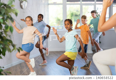 African girl moves in dance lesson and repeats movements behind unrecognizable teacher 140658522