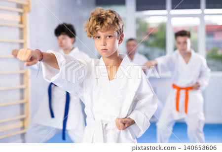 Preteen attendee of karate classes practicing kata standing in row with others 140658606