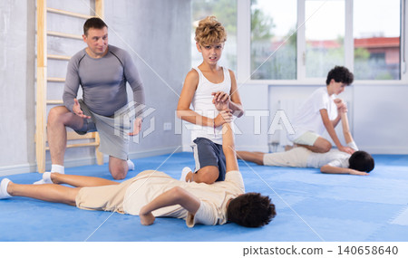 Diligent preteen student twisting his opponent's arm on the floor 140658640