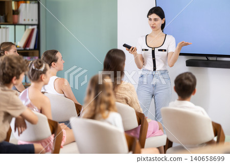 Young woman speaks to audience of teens and preteens listeners Young woman speaks to audience of teens and preteens listeners 140658699