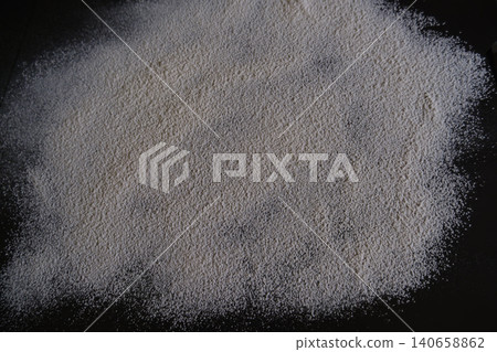White wheat flour scattered on black background top view  Sifted organic wheat flour spilled on a dark kitchen table. Smooth textured background for baking, cooking, pastry making, or piz 140658862