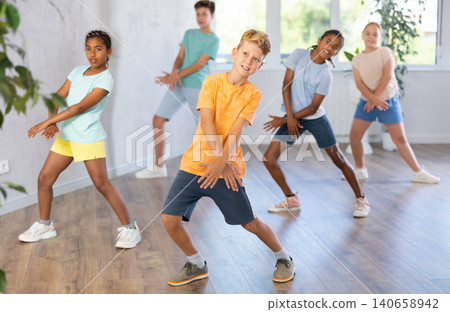 Cheerful tween boy dancing with group of children in choreography class Cheerful tween boy dancing with group of children in choreography class 140658942