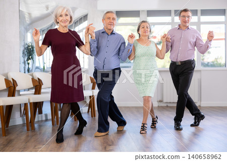 Smiling mature men and women dancing catalan typical Sardanas in dance salon 140658962