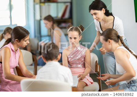 Teenagers and children working in teams on chairs monitored by teacher Teenagers and children working in teams on chairs monitored by teacher 140658982