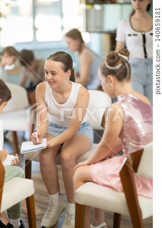 Teenagers and children working in teams on chairs monitored by teacher Teenagers and children working in teams on chairs monitored by teacher 140659181