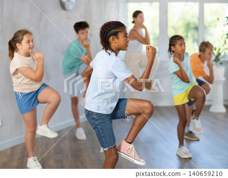 Active preteen boy practicing Hip-hop dance with other children and young trainer Active preteen boy practicing Hip-hop dance with other children and young trainer 140659210