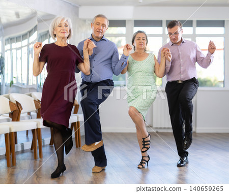 Smiling mature men and women dancing catalan typical Sardanas in dance salon Smiling mature men and women dancing catalan typical Sardanas in dance salon 140659265