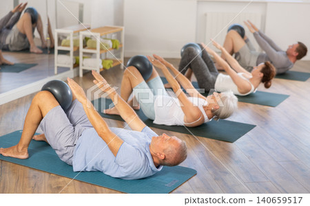 Elderly man doing pilates with softball Elderly man doing pilates with softball 140659517