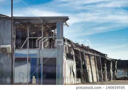 Exterior view of a severely damaged industrial building after a fire, showing charred walls and broken windows Exterior view of a severely damaged industrial building after a fire, showing charred walls and broken windows 140659595