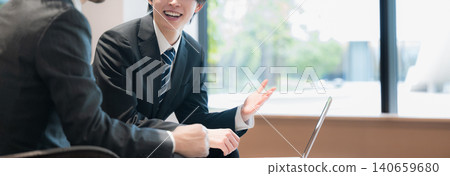 A young salesperson and the company president are having a meeting in a spacious office. The meeting is envisioned to include a proposal-based sales presentation and an explanation of a subordinate's project plan. 140659680