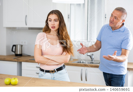 Disgruntled father scolds his adult daughter in the kitchen Disgruntled father scolds his adult daughter in the kitchen 140659691