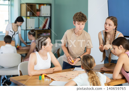 Teenagers playing board game with moving pieces at table 140659765