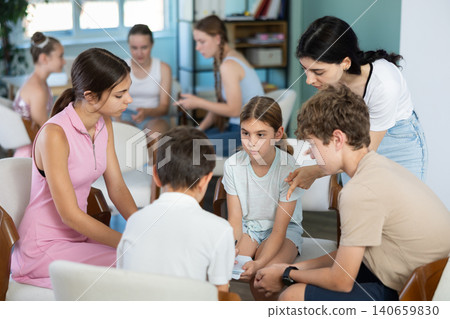 Teenagers and children working in teams on chairs monitored by teacher Teenagers and children working in teams on chairs monitored by teacher 140659830