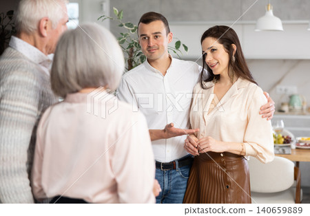 Smiling man introducing girlfriend to elderly parents at home Smiling man introducing girlfriend to elderly parents at home 140659889