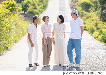 A senior couple and their married children stand side by side, both smiling. A senior couple and their married children stand side by side, both smiling. 140659923