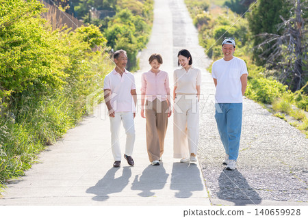 A senior couple and their married children walk together, chatting happily. A senior couple and their married children walk together, chatting happily. 140659928