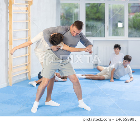 Judo teenager kids and trainer engaged in judo class in dojo at gym Judo teenager kids and trainer engaged in judo class in dojo at gym 140659993