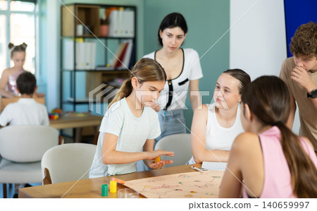 Preteen children and teenagers playing board game around table 140659997