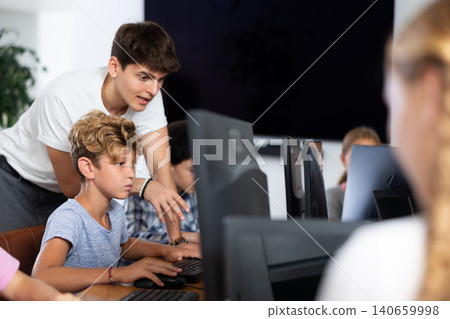 Positive man teacher together with the boy teaches how to work on computer Positive man teacher together with the boy teaches how to work on computer 140659998